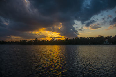 Scenic view of lake against dramatic sky during sunset