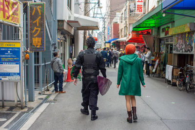 Rear view of people walking on city street