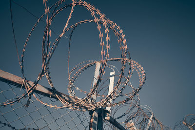 Low angle view of barbed wire against clear sky