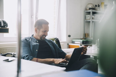 Confident businessman using laptop in creative office