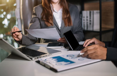 Midsection of woman using laptop on table