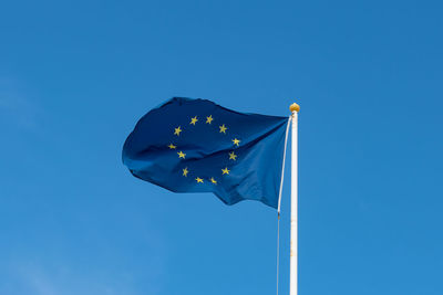 Low angle view of flag against clear blue sky