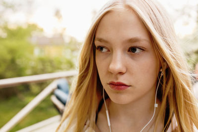 Thoughtful teenage girl listening to music in yard