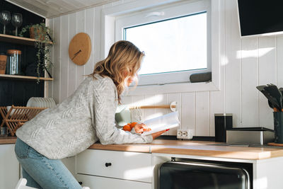 Side view of young woman using mobile phone while sitting at home