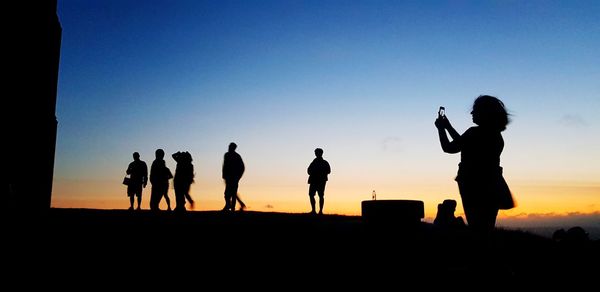 Silhouette people photographing against sky during sunset