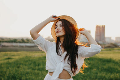 Woman wearing hat while standing on grass against sky