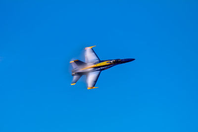 Low angle view of airplane flying against clear blue sky