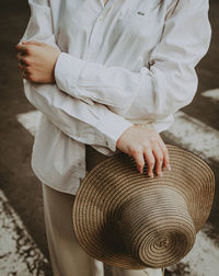 Midsection of woman holding hat standing outdoors