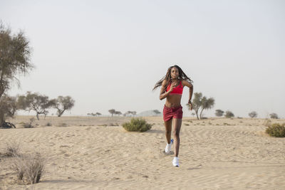 Full length of woman exercising in desert against sky