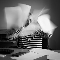 Portrait of mature woman throwing papers at office