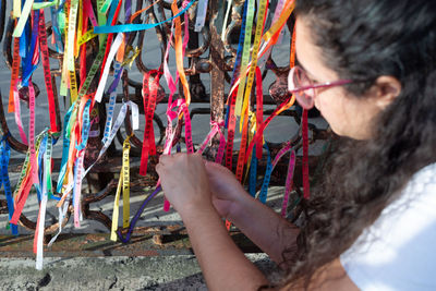 Portrait of a woman placing colored ribbons on the church grid. 