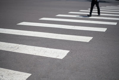 Businessman crossing urban street with graphic lines of the crosswalk in the foreground