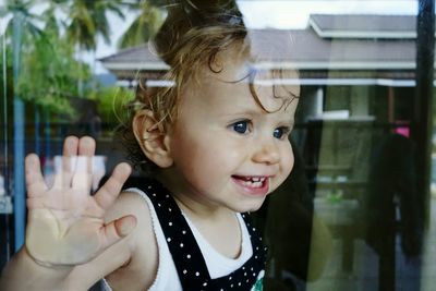 Close-up of cute girl looking through window