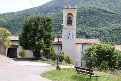 Built structure by trees and house against mountain