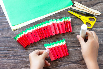 Midsection of person holding multi colored umbrella on table