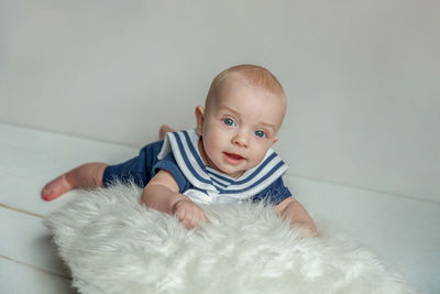Portrait of cute baby boy sitting on bed at home