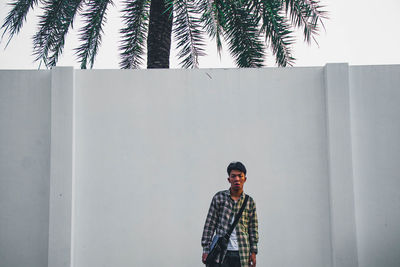 Portrait of young man standing against wall