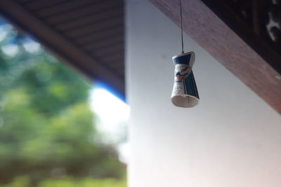 Low angle view of light bulb hanging against wall