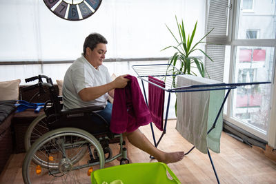 A disabled person on a wheelchair washes laundry