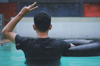 Young man gesturing peace sign in swimming pool