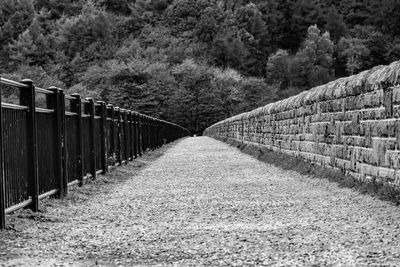 Empty footpath amidst wall and railing