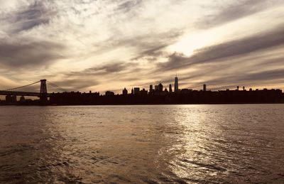 Silhouette of bridge over river against buildings