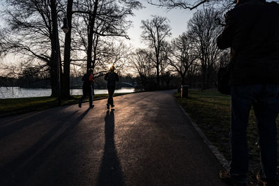 Rear view of man on road amidst trees against sky