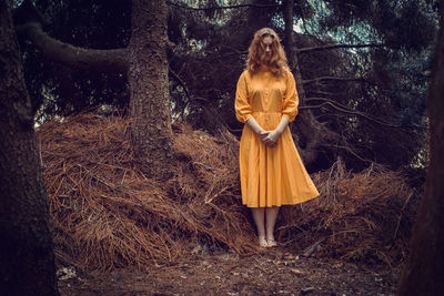 Woman standing on field against trees at forest