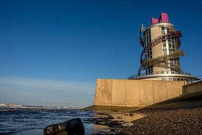 Lighthouse by sea against sky