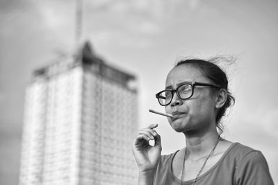 Woman smoking cigarette against sky