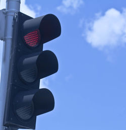 Low angle view of road signal against blue sky