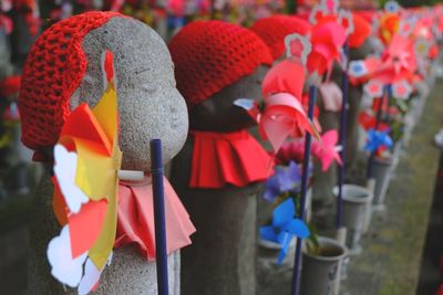 Close-up of pinwheel toys by sculptures with red knit hats