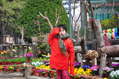 Rear view of woman standing by flowering plants