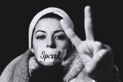 Woman with mouth taped giving peace sign