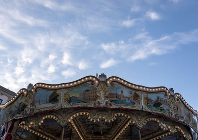 Low angle view of ferris wheel against cloudy sky