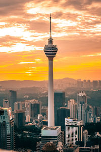 Communications tower in city during sunset