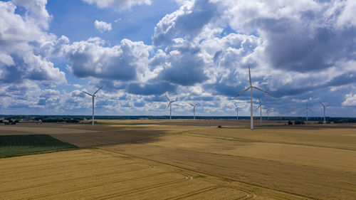 Windmills on field against sky