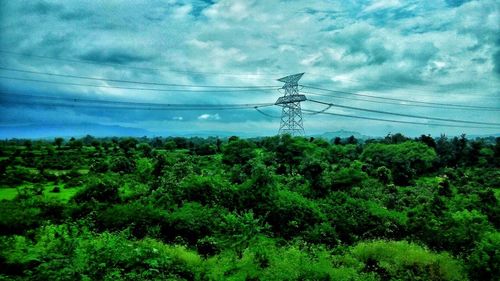 Electricity pylon against cloudy sky