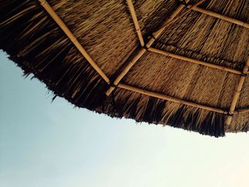 Low angle view of thatched roof against sky during sunny day