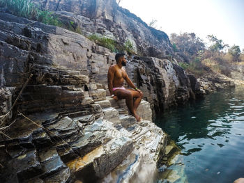 Full length of shirtless man standing on rock