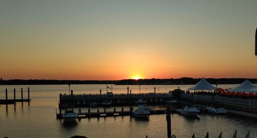 Boats moored in harbor at sunset