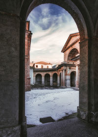 Historic building against sky seen through arch window