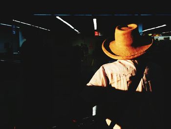 Man standing by illuminated lamp at night