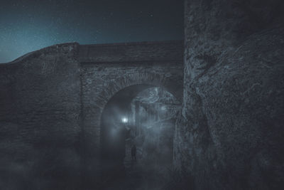 Arch bridge in old building against sky at night