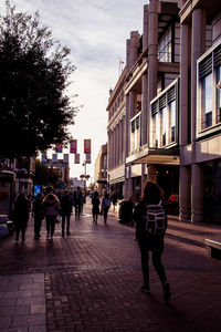 People walking on footpath by buildings in city