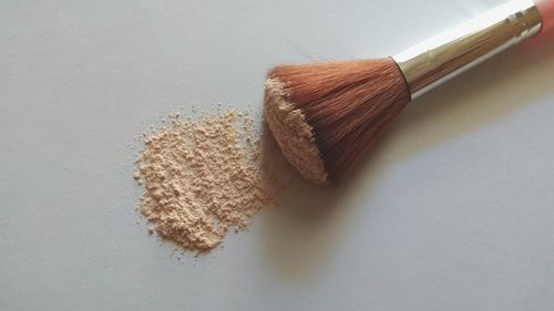 High angle view of make -up brush and powder on table