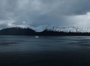 Scenic view of lake by snowcapped mountain against sky