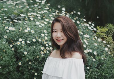 Portrait of smiling young woman by plants at public park