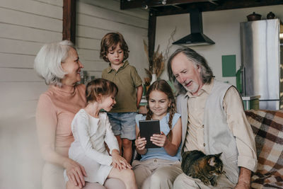 Girl sharing tablet pc with grandparents and siblings at home