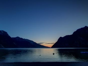 Scenic view of sea and mountains against clear sky